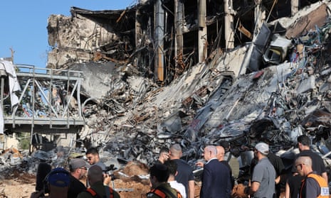 Benjamin Netanyahu and other officials view at a ruined building and debris