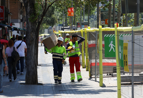 Workers walk under the sun during a heatwave in Barcelona, Spain, on July 1, 2025. [REUTERS/YONHAP]