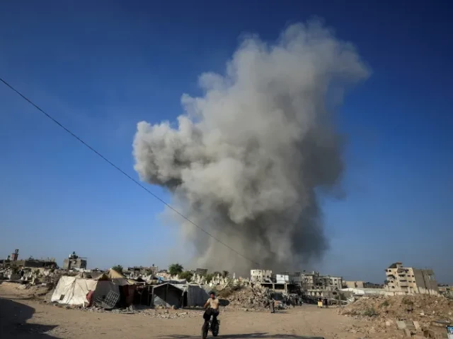 a palestinian man rides a bike as smoke rises following an israeli attack on gaza city august 24 2025 photo reuters
