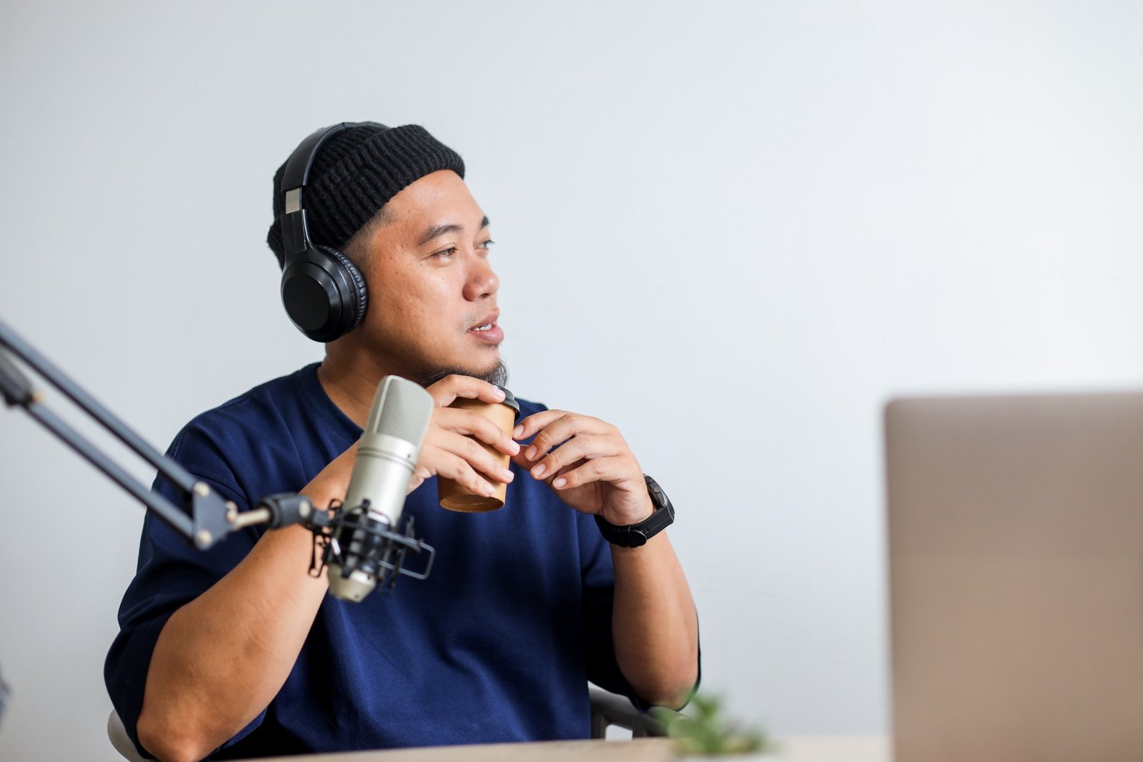 Asian Man with Headphones and Microphone Recording a Podcast at Home