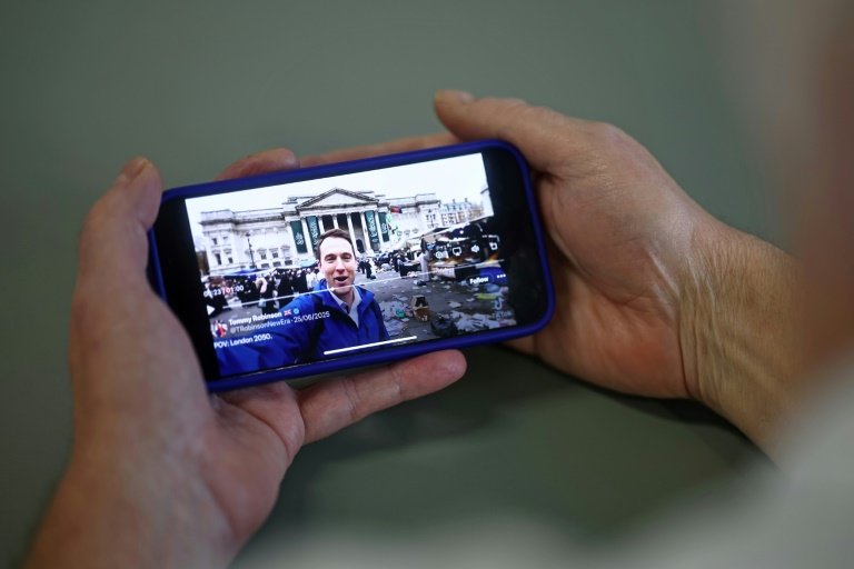 An AI-generated video of London in decline, shared on the social media site X account of British far-right activist Tommy Robinson, is viewed on a smart phone in London