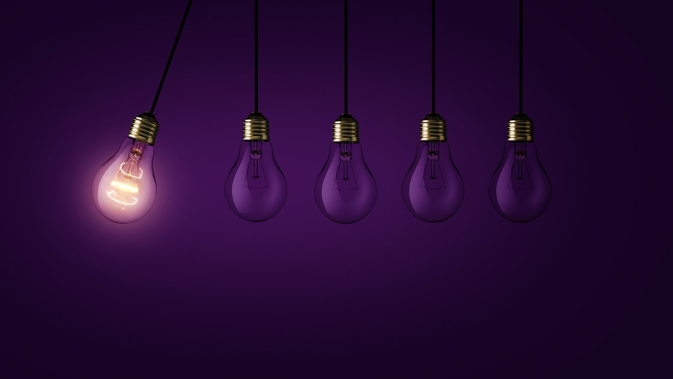 Creative light bulb lights up other extinguished light bulbs on a dark purple background, concept. Leadership, creative idea. Think differently. Start up