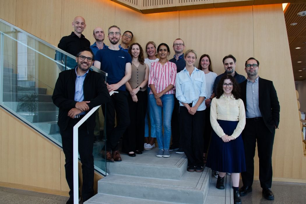 A group of approximately 15 people stand together on a staircase.