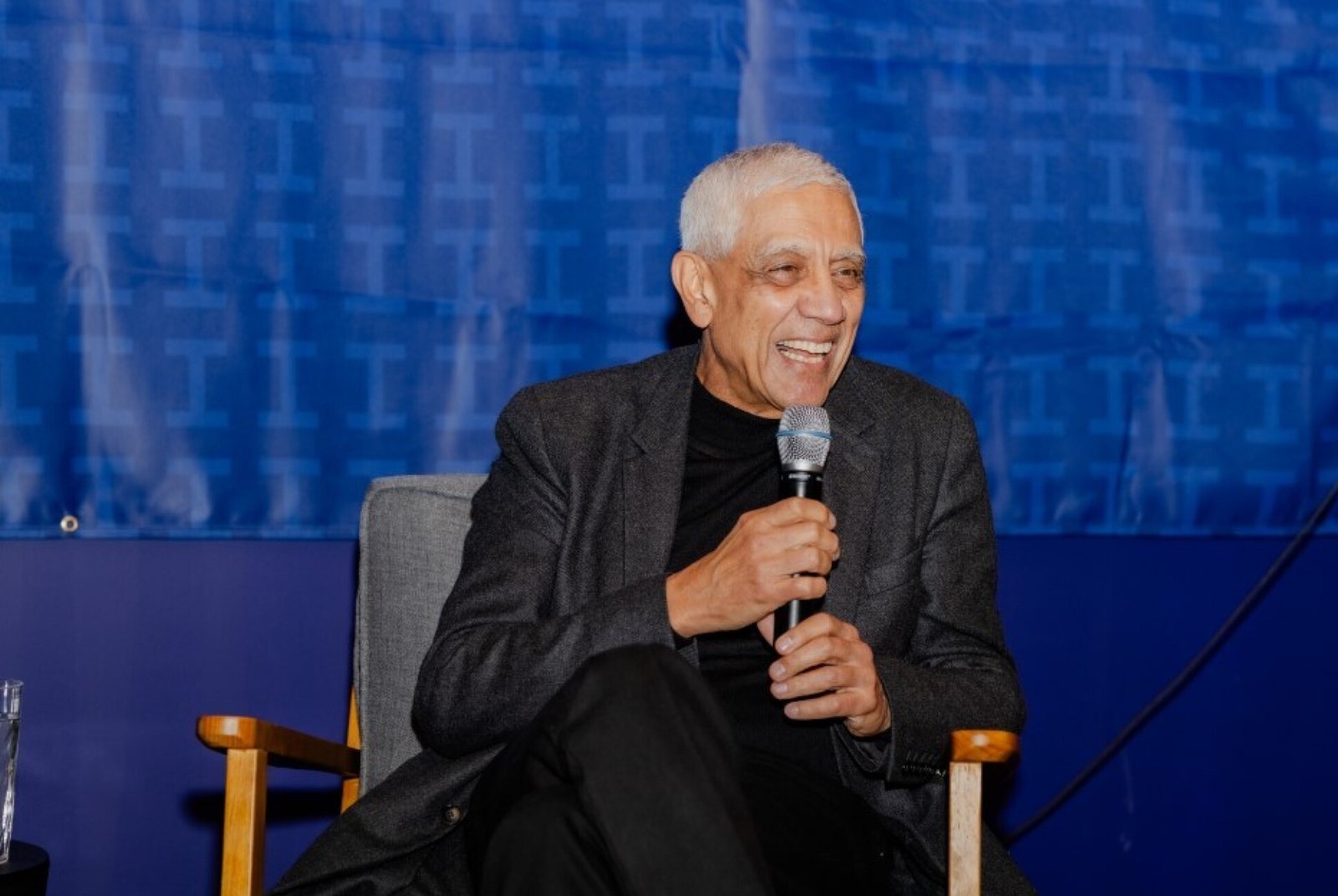 A man sitting down speaks into a microphone