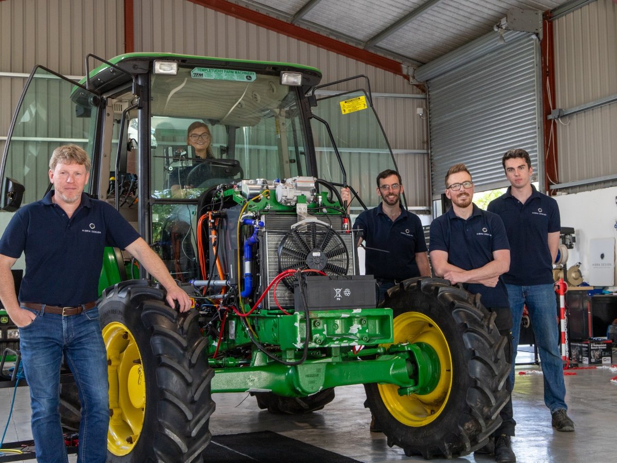 Five people pose around a technologically advanced tractor battery system for greentech.