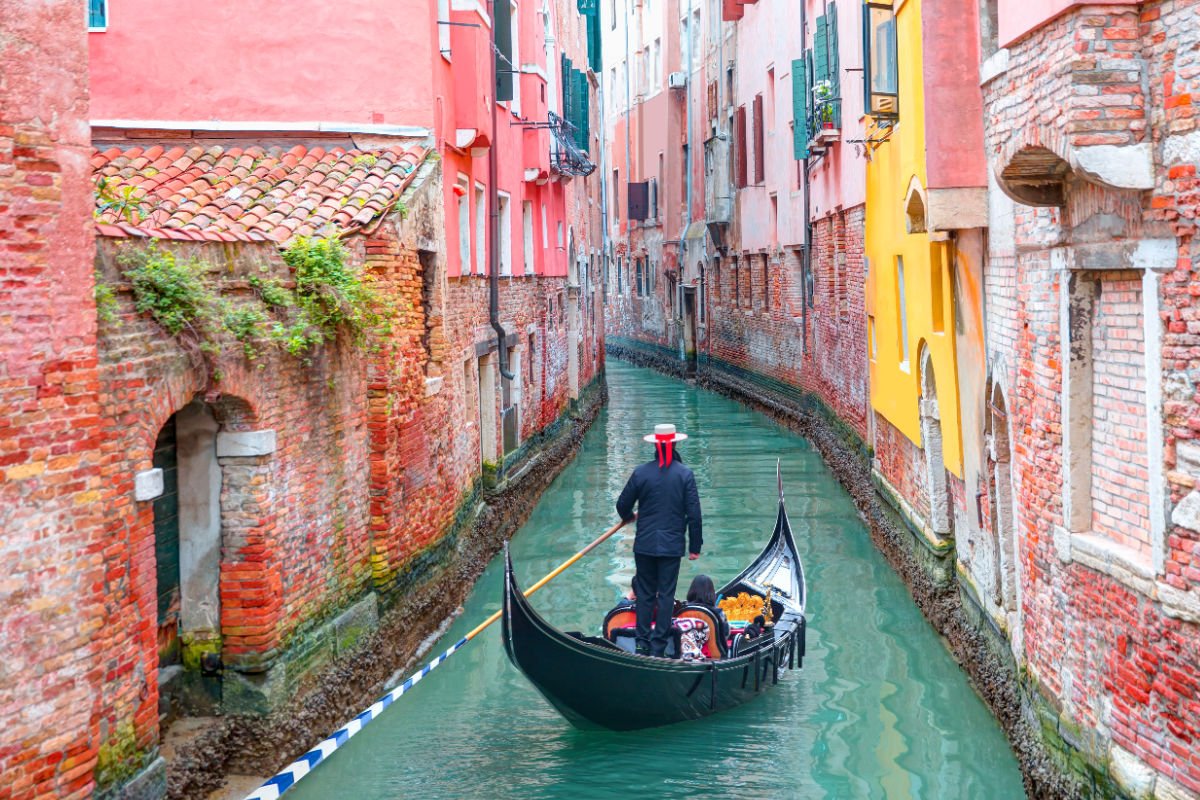 Gondalier guiding tourists through Venice canal