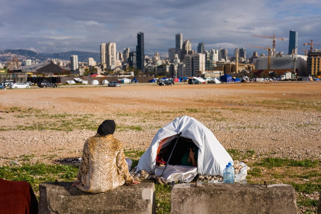 A displaced woman sits next her tent in an unofficial camp, erected along Beiruts seafront area on March 22, 2026. The Israeli military said it launched a wave of strikes on Beirut targeting the Iran-backed militant group Hezbollah, after urging residents of several areas to evacuate. Lebanon was pulled into the Middle East war when Hezbollah began firing rockets into Israel on March 2 to avenge the killing of Iran's supreme leader Ayatollah Ali Khamenei in US-Israeli strikes. Lebanon's health ministry says the latest war has killed more than 1,000 people in Lebanon and displaced more than one million more. (Photo by Dimitar DILKOFF / AFP)