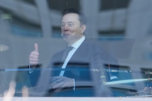 Elon Musk, left, gestures as he walks through a hallway inside the U.S. District Court in Oakland, Calif., Wednesday, April 29, 2026. (AP Photo/Godofredo A. V&aacute;squez)