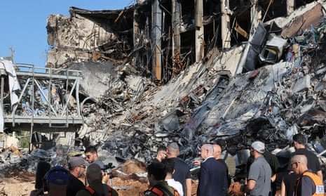 Benjamin Netanyahu and other officials view at a ruined building and debris