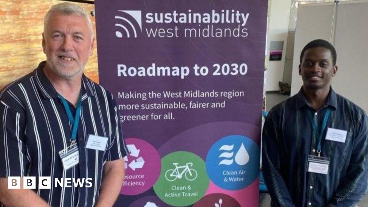 Two men pose either side of a banner stating sustainability West Midlands, Roadmap to 2030. The men are both wearing striped shirts and lanyards. The one on the left has grey hair and a beard and the other has close cropped black hair.