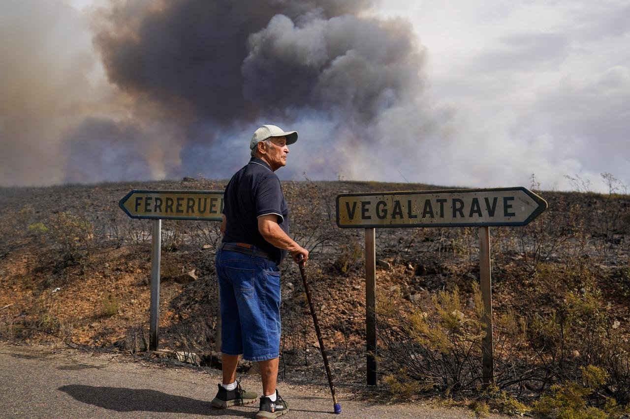 An elderly man walks on a road as smoke from a wildfire rises on the horizon near Losacio, north of Zamora, Spain, August 12, 2025. (AFP Photo)