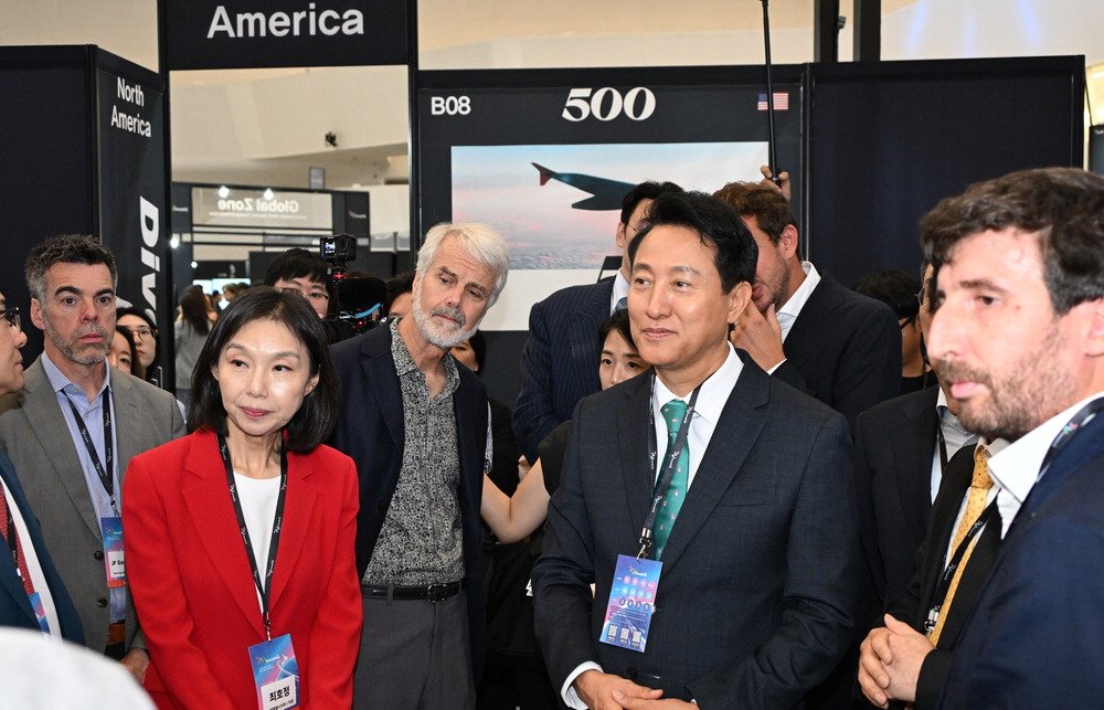 Seoul Mayor Oh Se-hoon (second right) is listening to explanations at a startup exhibition booth with Tesla co-founder Martin Eberhard (third right) at the opening ceremony of Tri Everything 2025 held at Dongdaemun Design Plaza (DDP) on Sunday. Seoul City