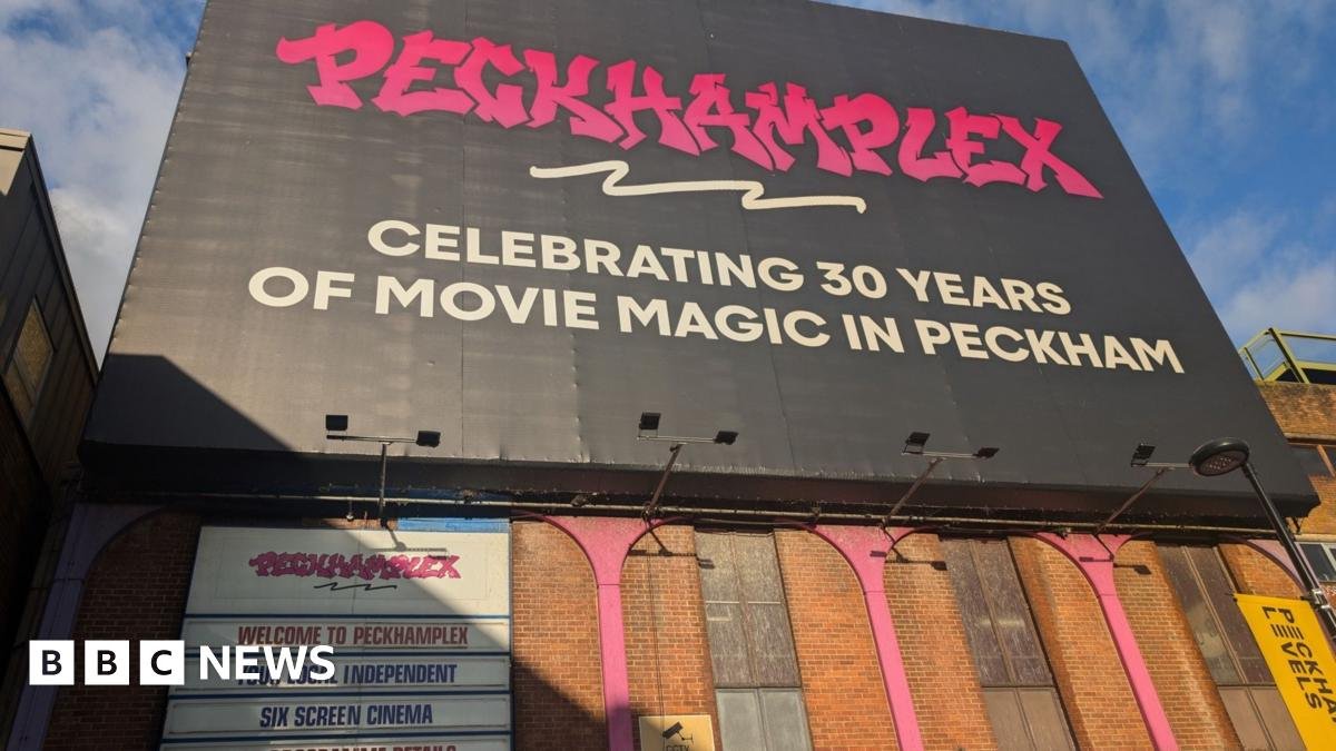 A sunlit image of the front of the Peckhamplex cinema including a pink graffiti style logo for Peckhamplex on a black background which states the cinema is celebrating 30 years of movie magic in Peckham