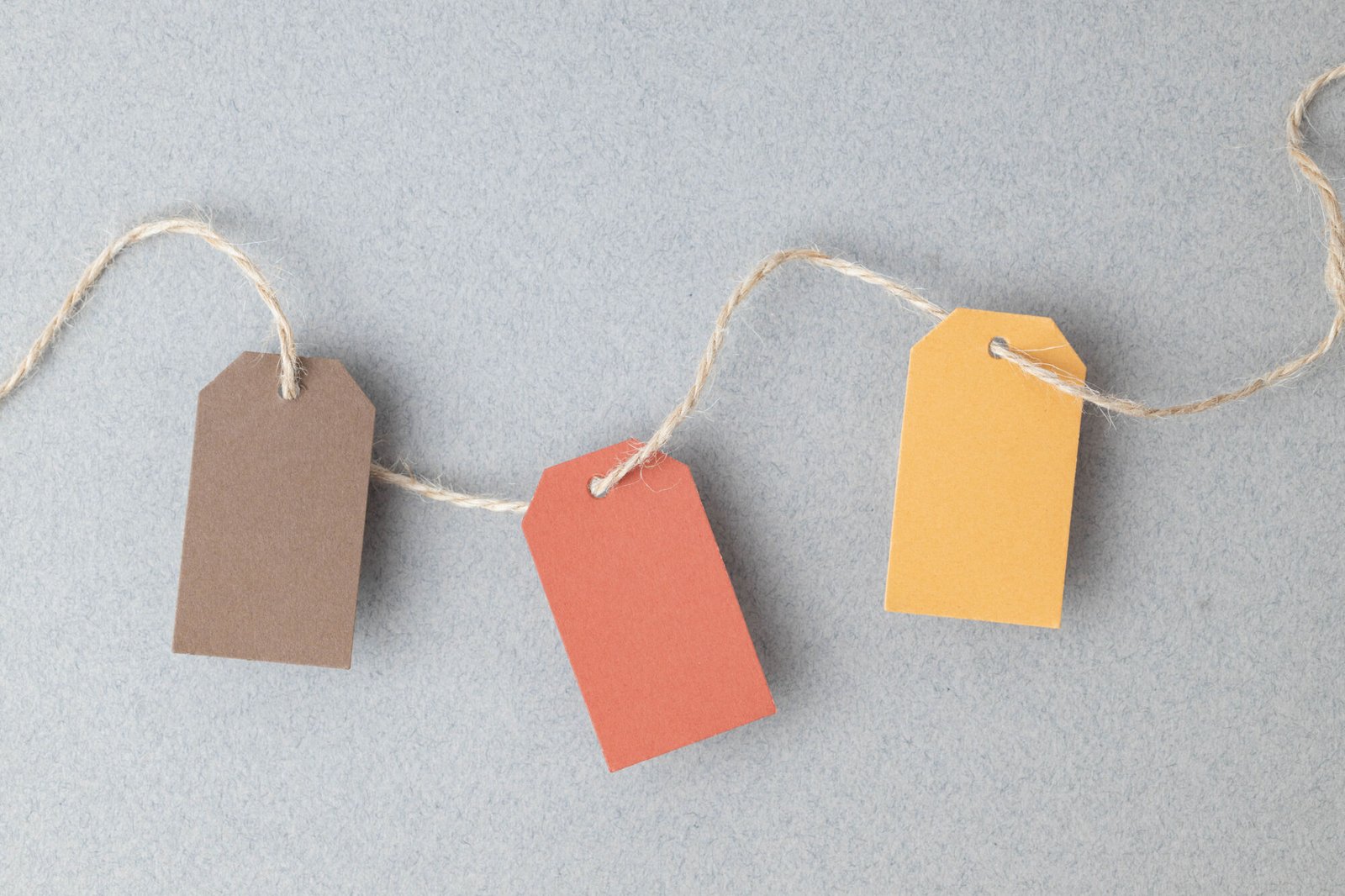 Autumn color palette, blank gift tags with jute twine string on a gray textured surface with copy space.