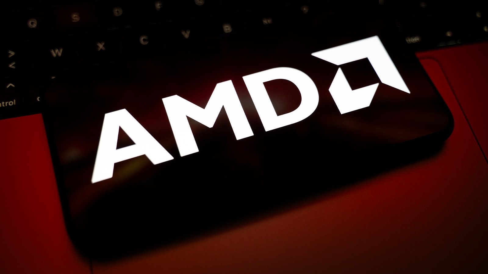 AMD logo and branding pictured on a smartphone screen placed on top of a desktop keyboard.