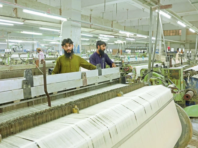 workers inspect loom machines weaving fabric at a textiles manufacturer in karachi photo reuters