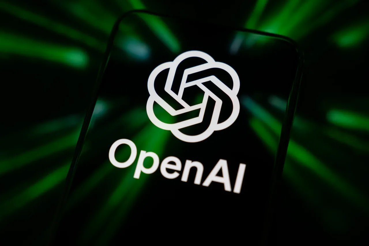 The OpenAI logo displays on a smartphone screen reflecting green beams. (Photo by Samuel Boivin/NurPhoto via Getty Images)