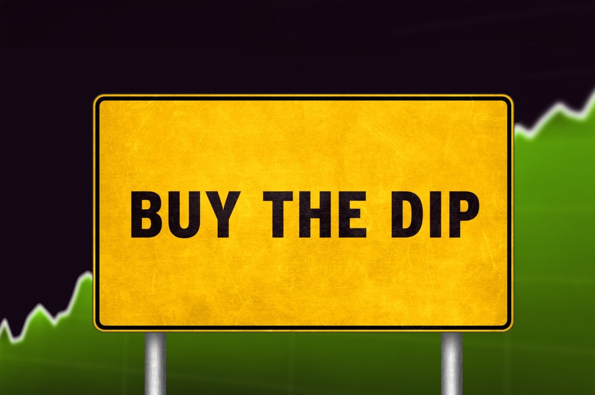 A yellow road sign that says "Buy the dip."