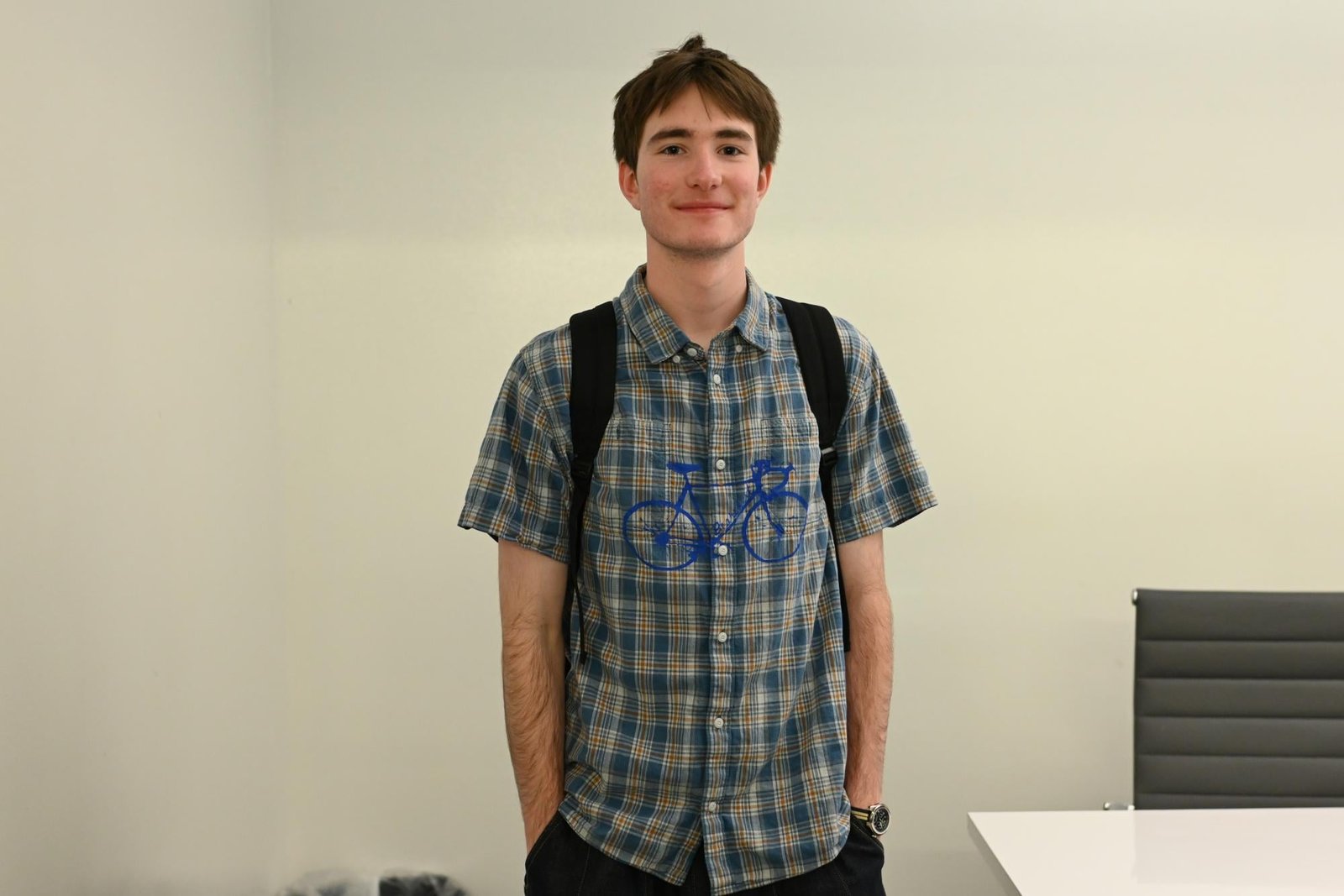 A person with a checkered pattern shirt with a bike on it smiles for a photo.