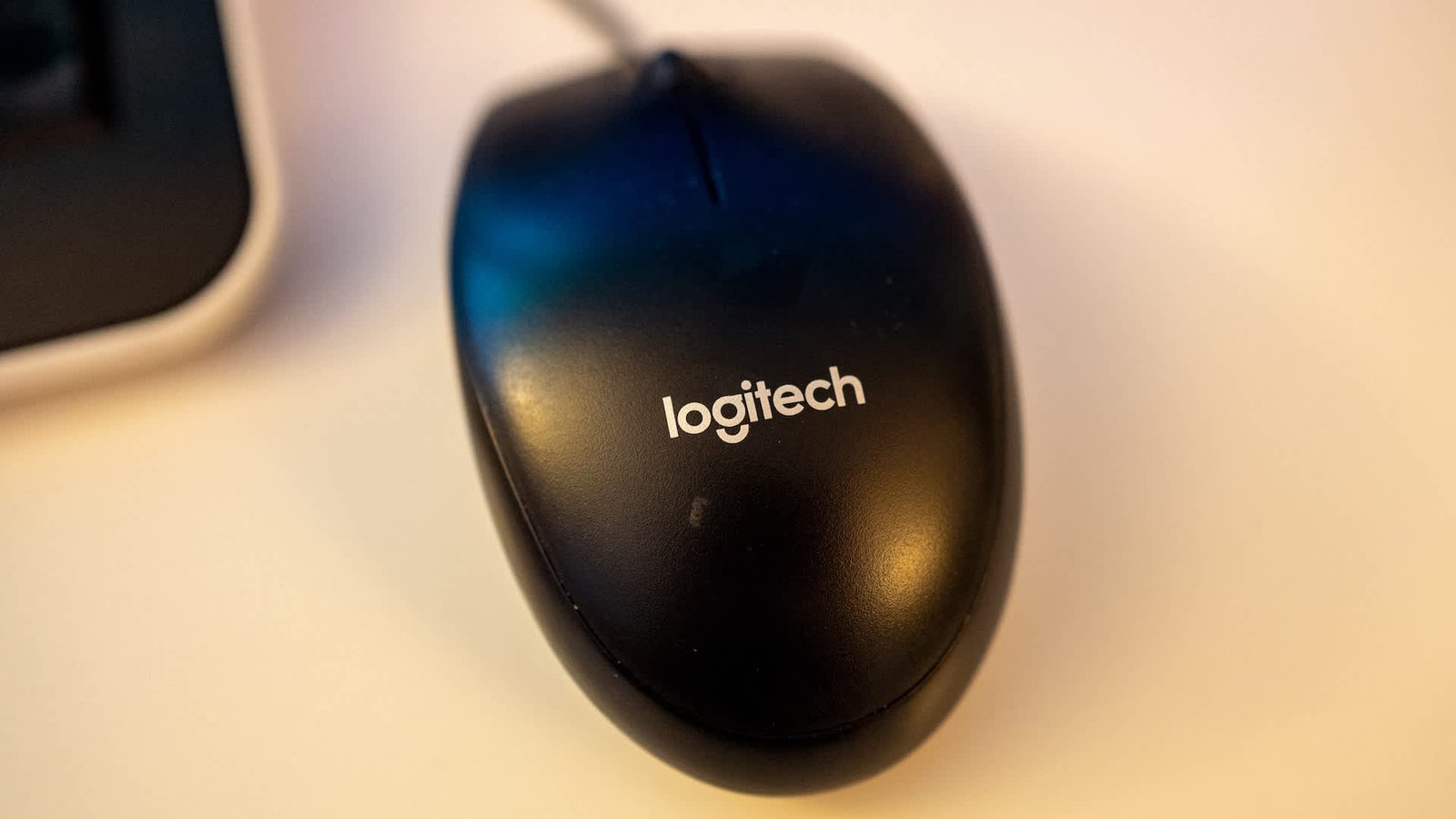 A black Logitech computer mouse on a light-colored surface.